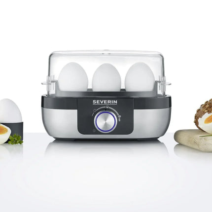 Severin äggkokare med fyra kokta ägg, brödskiva och halvt ägg på vitt bord, Nordic Cookware