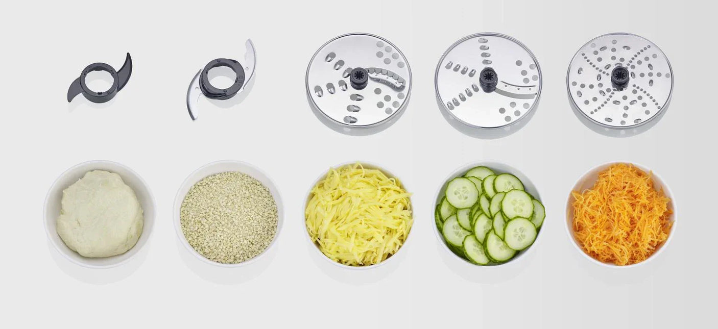 Tillbehör till köksmaskin från Nordic Cookware med olika rivskivor och skålar med ingredienser.