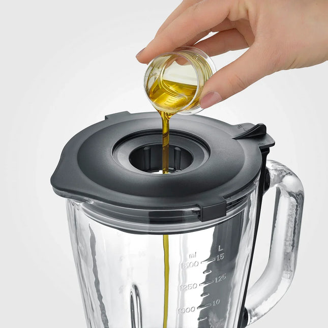 Hand häller olja i mixerbägare med lock, köksutrustning från Nordic Cookware