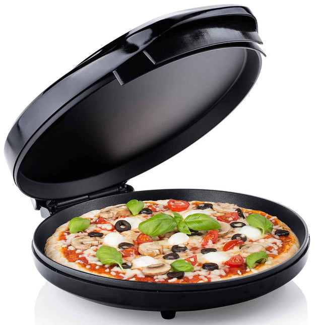 Svart pizzaugn från Nordic Cookware med en färskgräddad pizza, basilika och grönsaker