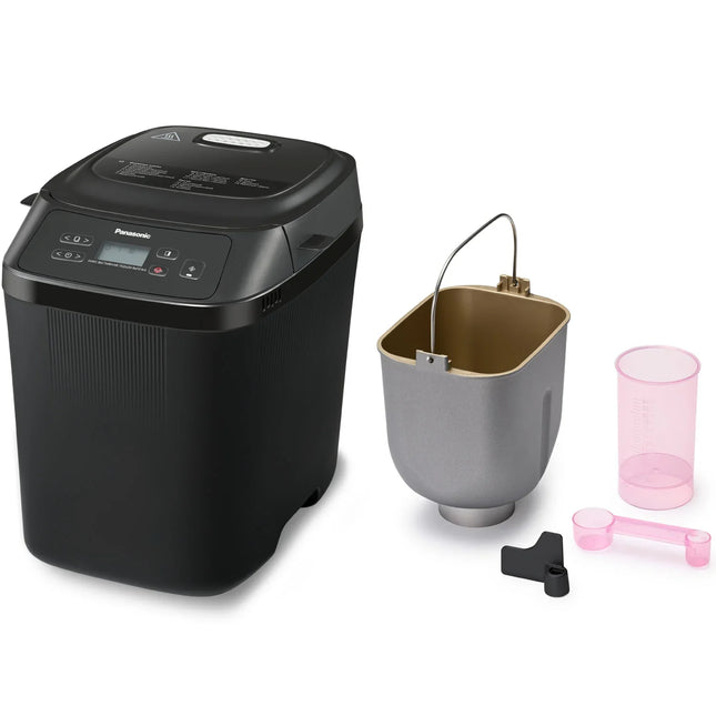Svart brödmaskin Panasonic med tillbehör, bakform, måttkopp och sked på vit bakgrund.